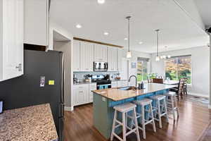 Kitchen featuring light stone counters, dark hardwood / wood-style flooring, white cabinetry, sink, and stainless steel appliances