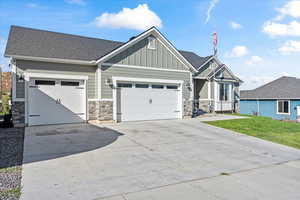 Craftsman inspired home featuring a front yard and a garage