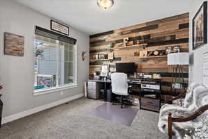 Carpeted home office featuring wooden walls