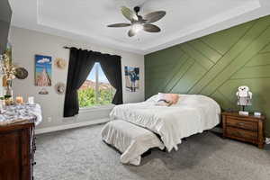 Bedroom with ceiling fan, a raised ceiling, and carpet