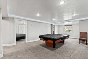 Recreation room featuring light carpet, a textured ceiling, and billiards