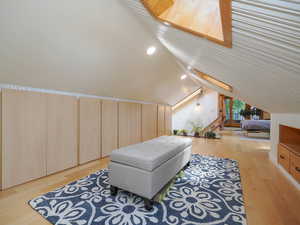 Bedroom with light wood-type flooring and lofted ceiling with skylight