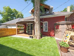 Rear view of house featuring a balcony, a patio area, and a lawn