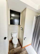 Bathroom featuring a shower with curtain, hardwood / wood-style flooring, and toilet