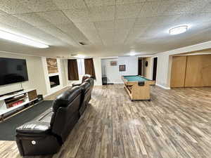 Recreation room featuring wood-type flooring, a fireplace, and billiards