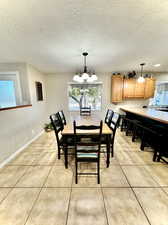 Tiled dining area with a notable chandelier and a textured ceiling