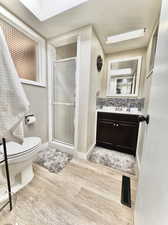 Bathroom featuring vanity, toilet, a shower with door, and hardwood / wood-style flooring