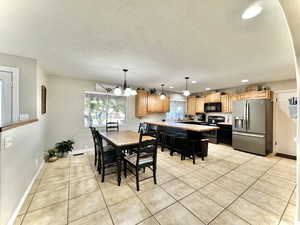 Dining area with a textured ceiling, light tile patterned flooring, an inviting chandelier, and sink