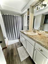 Bathroom featuring vanity, a raised ceiling, a notable chandelier, and hardwood / wood-style flooring