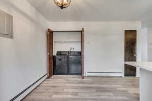 Interior space with light wood-type flooring, baseboard heating, and washing machine and clothes dryer