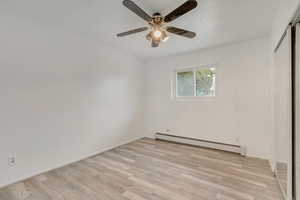 Empty room with ceiling fan, light hardwood / wood-style flooring, and a baseboard radiator