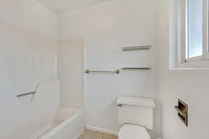 Bathroom featuring tile patterned flooring, toilet, and a tub