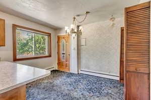 Unfurnished dining area with a baseboard radiator, a chandelier, and a textured ceiling