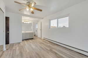 Unfurnished bedroom with connected bathroom, ceiling fan, light wood-type flooring, and a baseboard heating unit