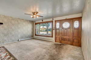 Entrance foyer featuring a baseboard heating unit, light carpet, and ceiling fan