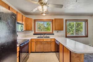 Kitchen with black appliances, kitchen peninsula, ceiling fan, and a wealth of natural light