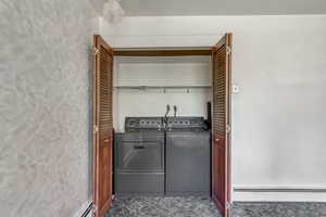 Laundry room with washer and clothes dryer and a baseboard radiator