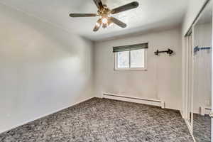 Empty room featuring ceiling fan, baseboard heating, and carpet