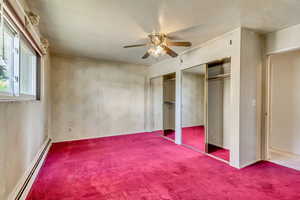 Unfurnished bedroom featuring ceiling fan, a textured ceiling, baseboard heating, and carpet