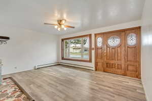 Foyer entrance featuring baseboard heating, ceiling fan, and light hardwood / wood-style floors