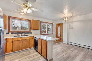 Kitchen featuring a baseboard heating unit, ceiling fan with notable chandelier, sink, black dishwasher, and kitchen peninsula