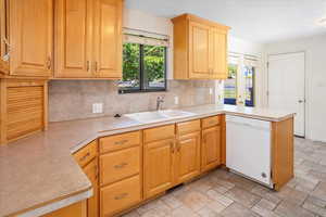 Kitchen featuring a healthy amount of sunlight, kitchen peninsula, dishwasher, and sink