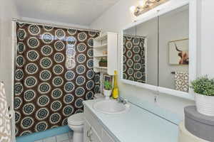 Bathroom featuring toilet, vanity, tile patterned floors, and a textured ceiling