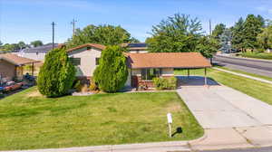 Single story home featuring a front yard and a carport