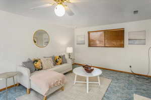 Carpeted living room with ceiling fan