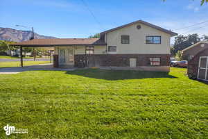 Back of house featuring a mountain view, a carport, a yard, and central air condition unit