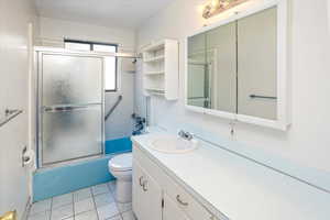 Full bathroom with tile patterned floors, shower / bath combination with glass door, vanity.