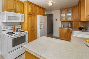 Kitchen with sink, white appliances, and a textured ceiling