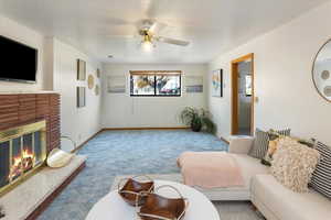 Living room featuring ceiling fan, light colored carpet, and a fireplace