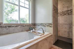 Bathroom featuring tiled tub and a healthy amount of sunlight