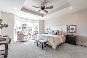 Bedroom featuring ceiling fan, light colored carpet, a raised ceiling, and wooden ceiling