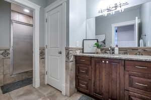 Bathroom with tile walls, a shower with door, and vanity