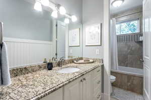 Full bathroom featuring vanity, shower / bath combo with shower curtain, and toilet