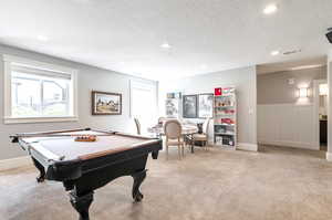 Game room with light carpet, a textured ceiling, and billiards