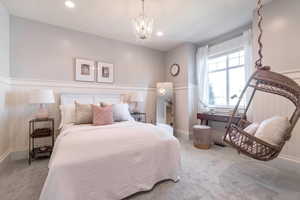 Carpeted bedroom featuring a notable chandelier