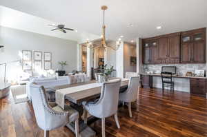 Dining area with ceiling fan with notable chandelier and dark wood-type flooring