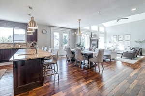 Interior space with a textured ceiling, ceiling fan with notable chandelier, sink, and dark wood-type flooring