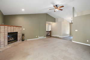 Unfurnished living room with high vaulted ceiling, carpet, ceiling fan, and a fireplace