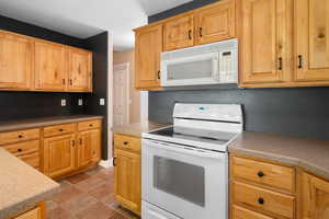 Kitchen with a textured ceiling and white appliances