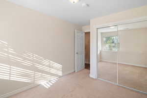 Unfurnished bedroom with light carpet and a closet