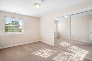 Unfurnished bedroom with light carpet and a closet