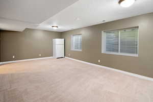 Empty room with a textured ceiling and light carpet