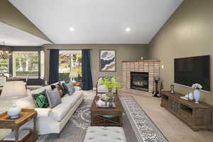 Carpeted living room featuring a brick fireplace, a chandelier, and vaulted ceiling