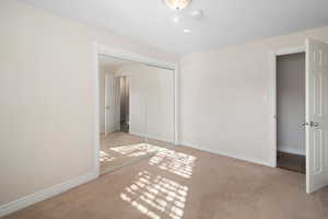 Unfurnished bedroom with light colored carpet and a closet