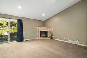 Unfurnished living room featuring a brick fireplace, light carpet, and vaulted ceiling