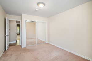 Unfurnished bedroom featuring light colored carpet and a closet